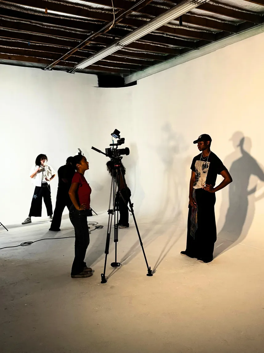 Fashion models, a camera operator and studio lighting on the set of a fashion shoot.